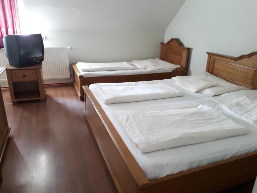 two beds in a room with a tv on a table at Horváthkert Panzió és Étterem in Bogács