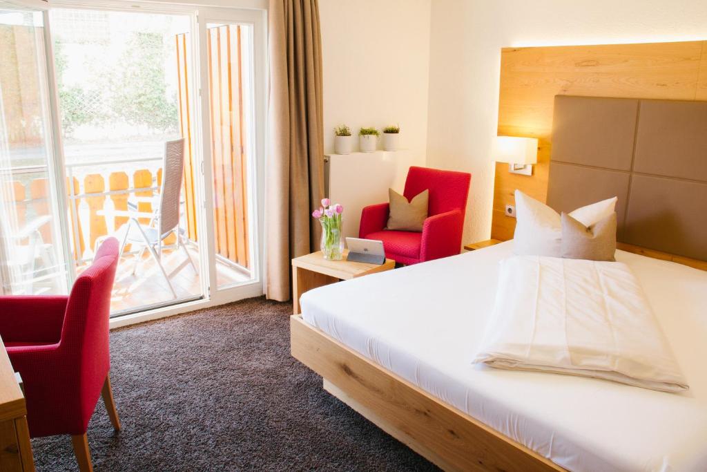 a hotel room with a bed and chairs and a balcony at Hotel-Restaurant Sennhütte im Herzen des Südschwarzwalds in Kleines Wiesental