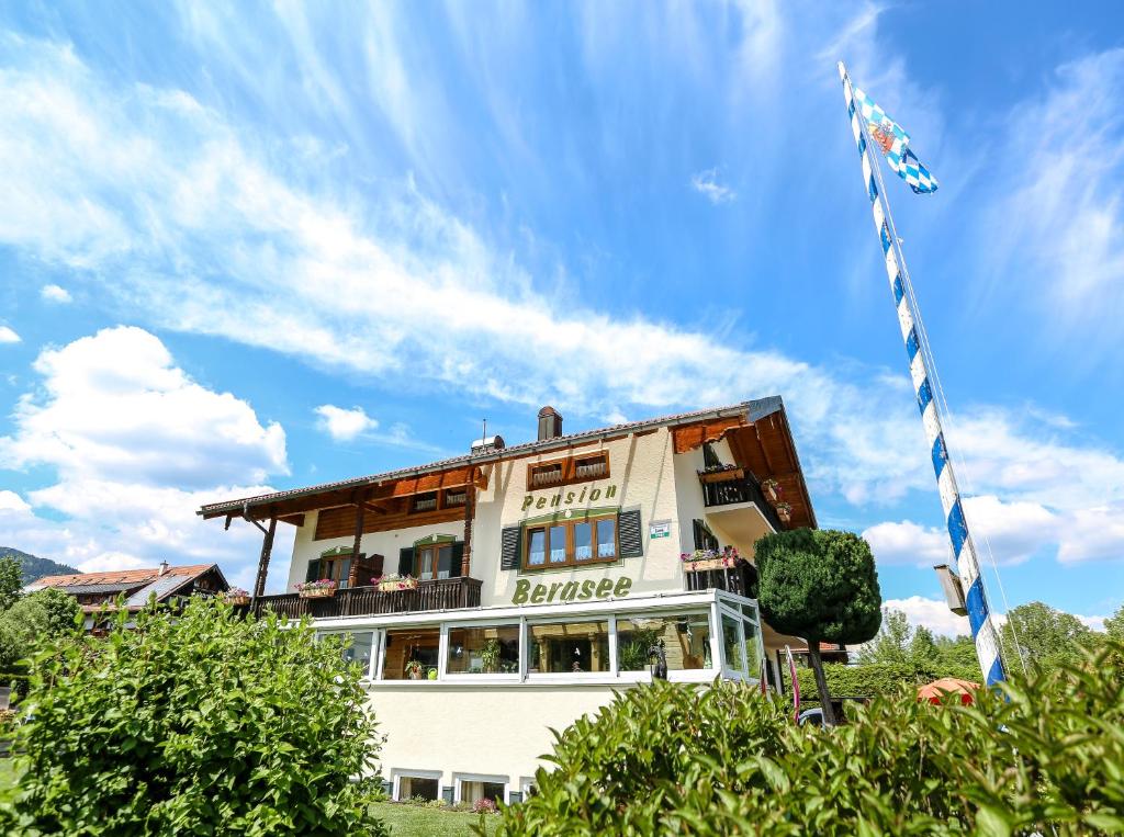 a white building with a flag on top of it at Pension Bergsee in Bad Wiessee