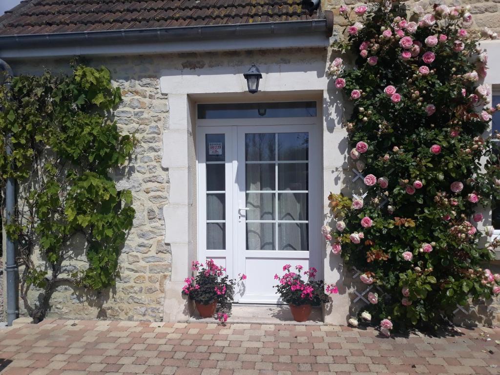a white door with flowers on a stone house at Chambres d'Hotes Elvire et Laurent Barbey in Sainte-Marie-du-Mont