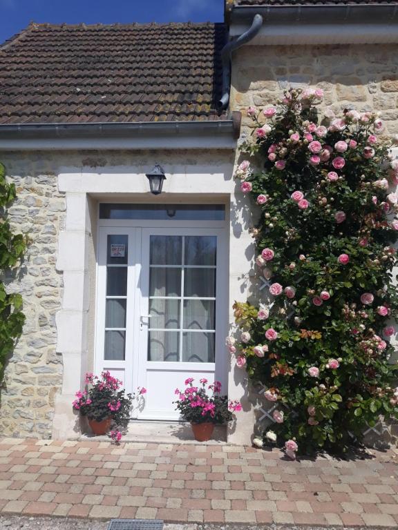 a house with a white door with roses on it at Chambres d'Hotes Elvire et Laurent Barbey in Sainte-Marie-du-Mont