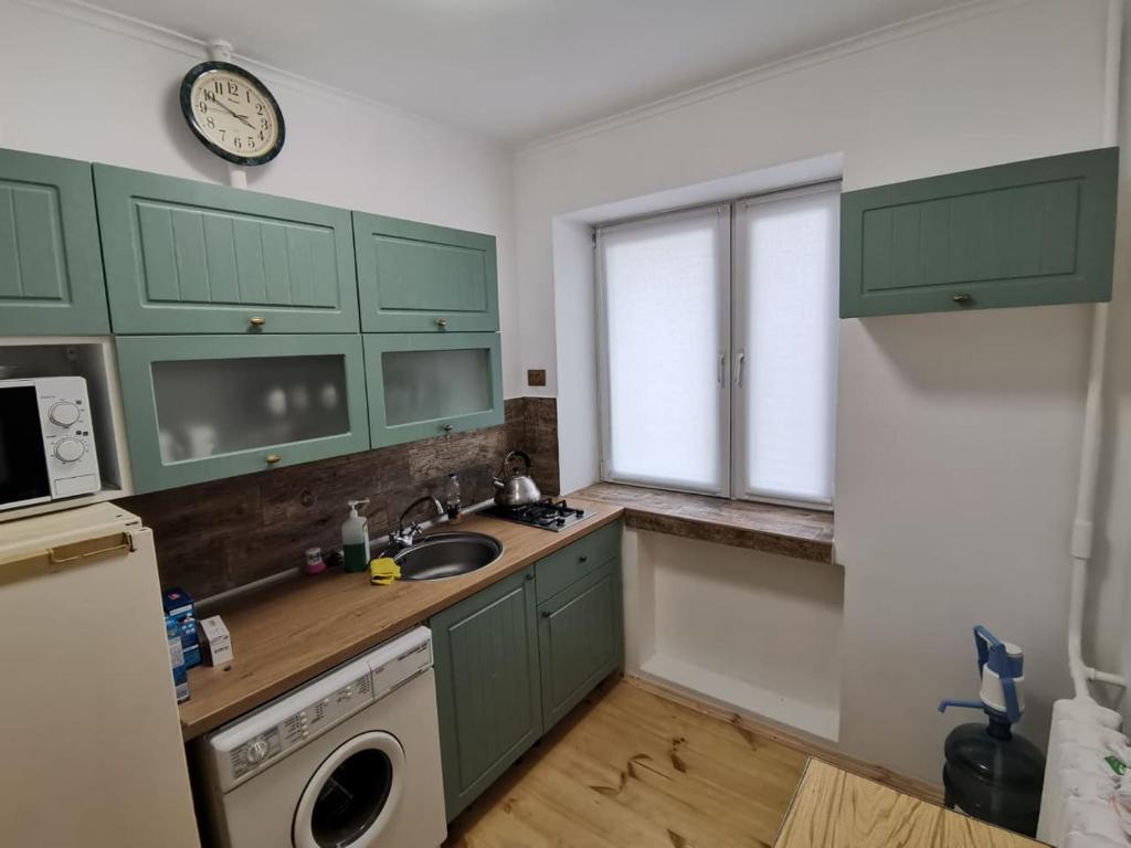 eine Küche mit grünen Schränken, einem Waschbecken und einem Fenster in der Unterkunft квартира біля лікарні мечнікова in Dnipro