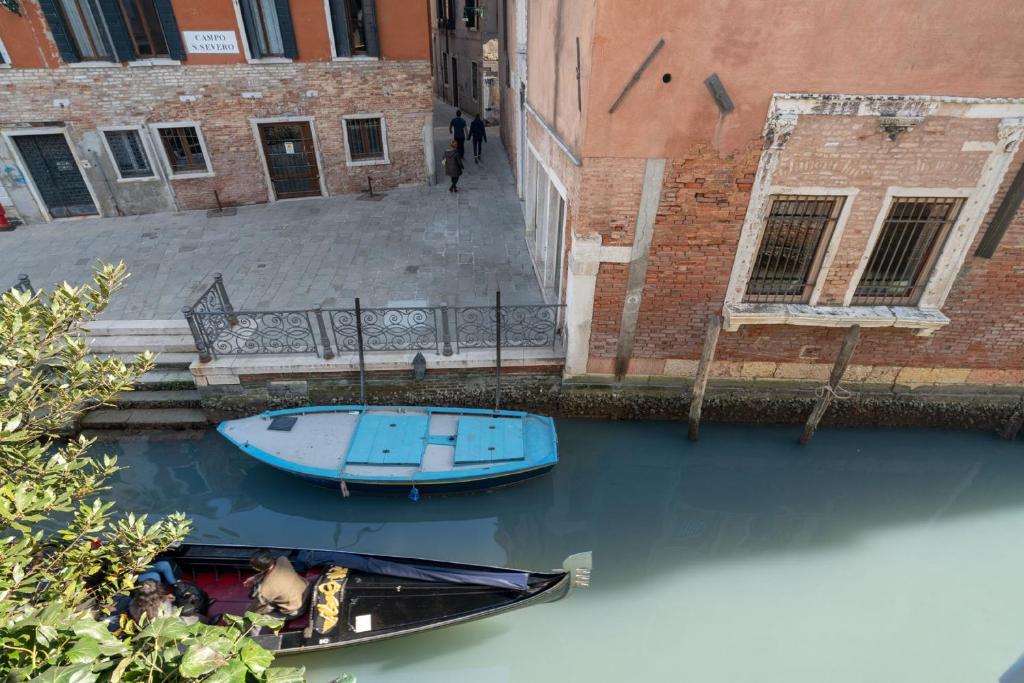 un bateau bleu dans l'eau à côté d'un bâtiment dans l'établissement Apartments in San Marco with Canal View by Wonderful Italy, à Venise