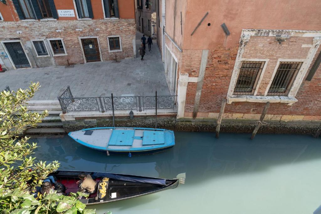 a blue boat in the water next to a building at Apartments in San Marco with Canal View in Venice