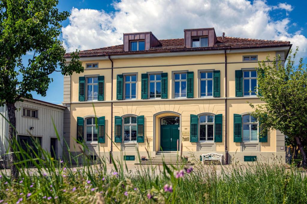 ein altes Haus mit grünen Rollläden an einem Gebäude in der Unterkunft VILLA TAEGERMOOS in Tägerwilen