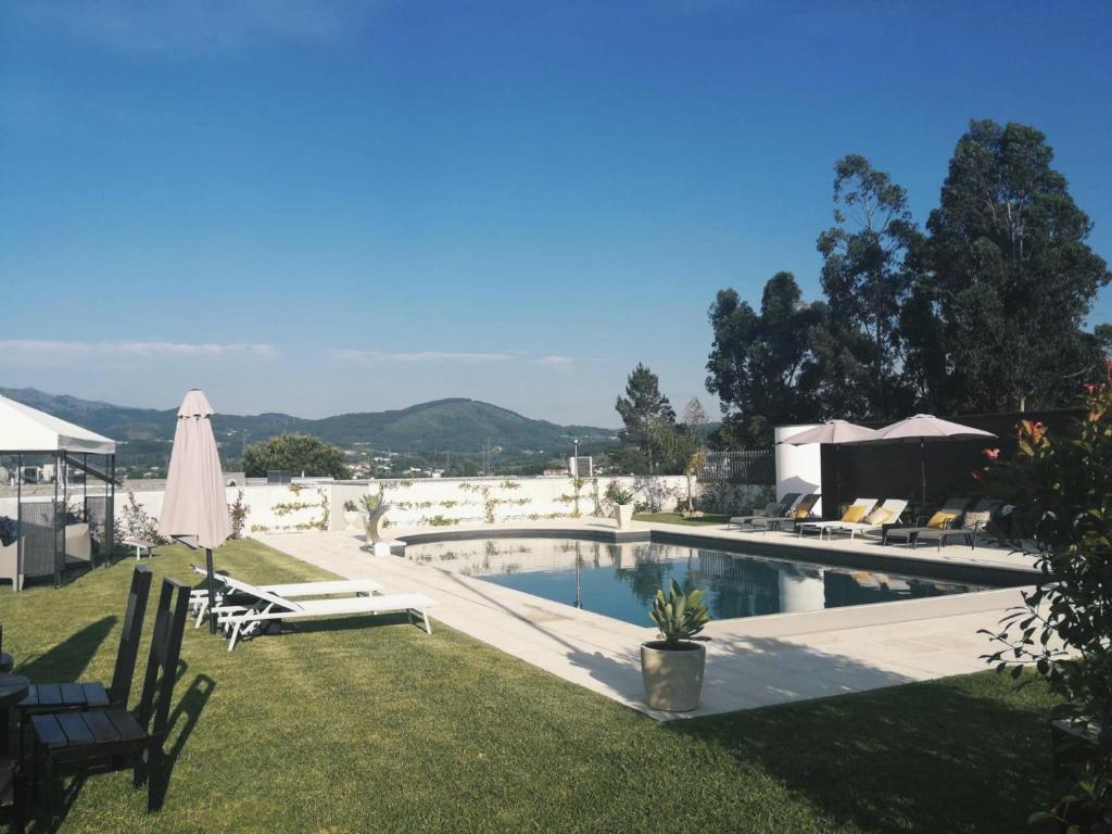a swimming pool with lawn chairs and an umbrella at Casa d'Amares in Amares