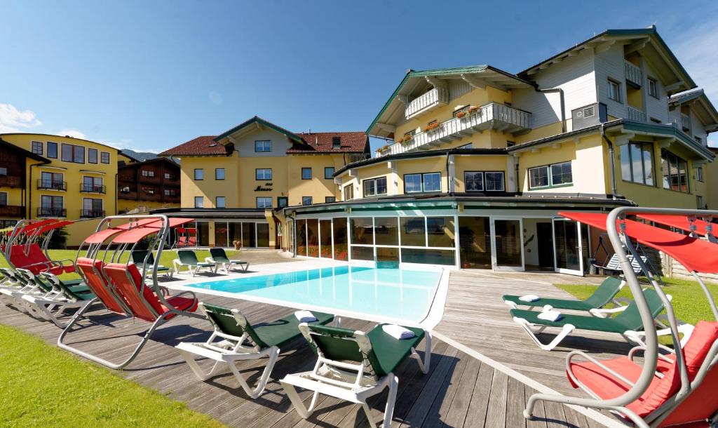 a building with a swimming pool and chairs and a house at Hotel Moser in Schladming