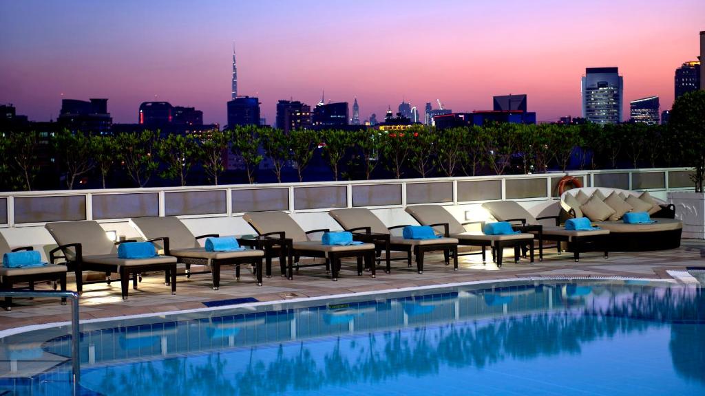 eine Hotelterrasse mit Pool und Skyline der Stadt in der Unterkunft Crowne Plaza Dubai Deira, an IHG Hotel in Dubai