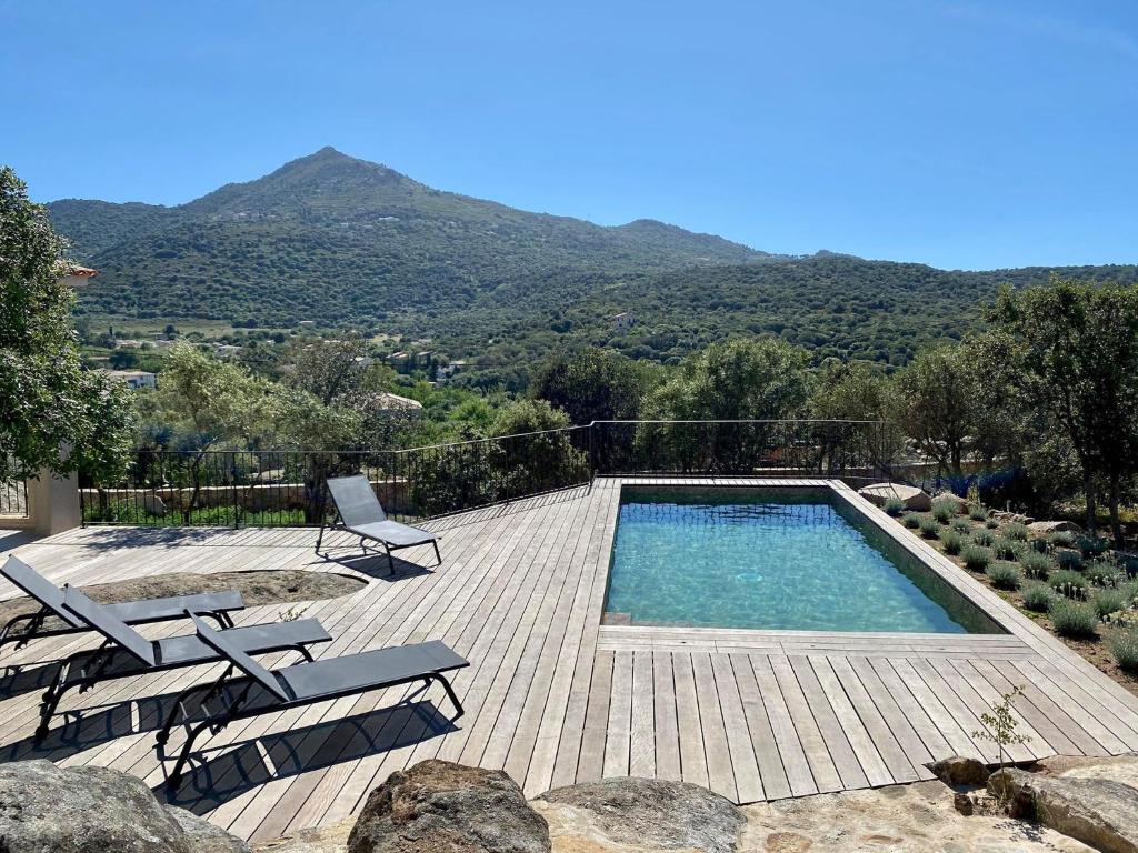 una piscina con terraza, sillas y montañas en Villas Celia, en Monticello