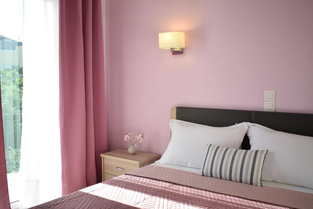 um quarto com uma cama com paredes cor-de-rosa e uma janela em Mirto Beach Hotel & Restaurant em Paralia Vrachou