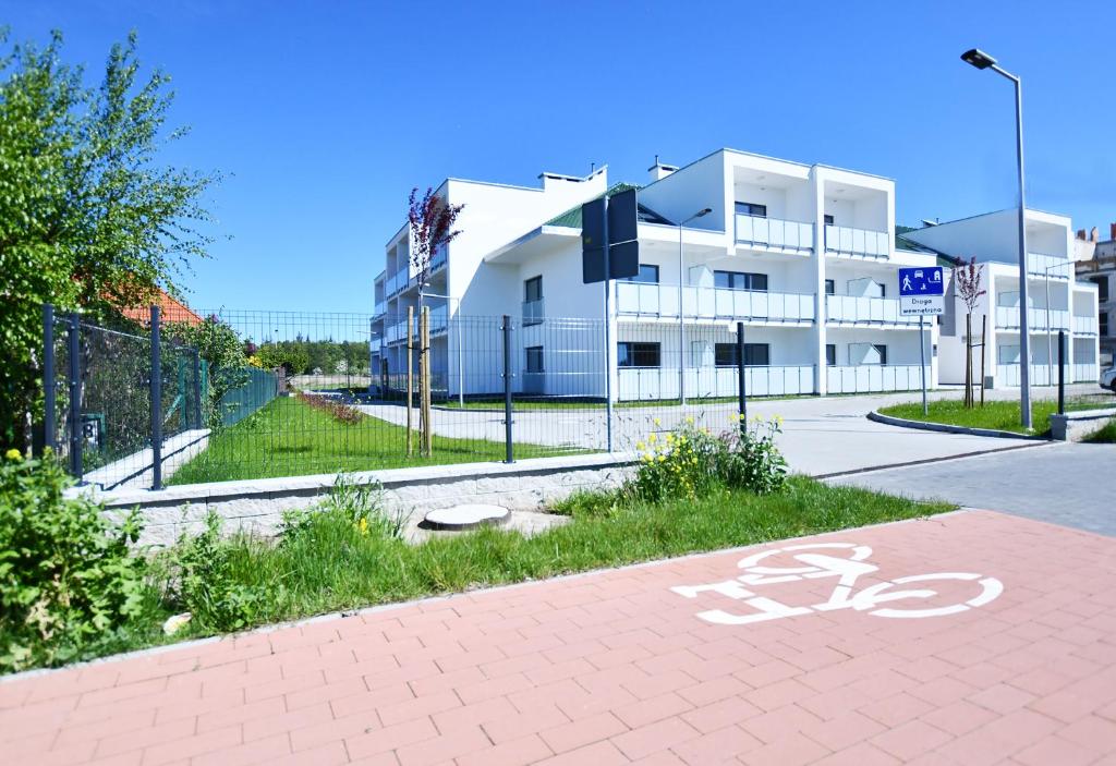 a white building with a bike sign on the street at Sunset Resort, Nadmorska 106 in Grzybowo