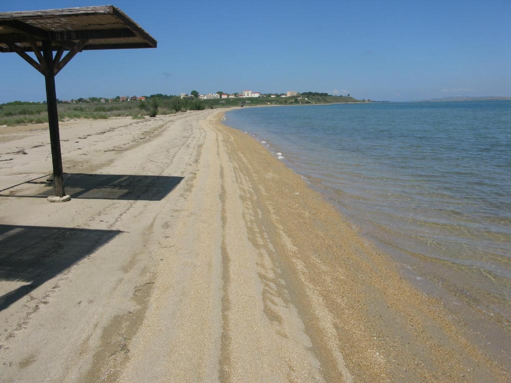 uma praia arenosa com um guarda-sol e a água em Queen's beach apartment Sabunike Nin - Green street II em Nin