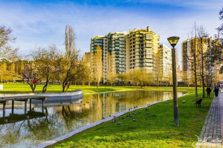 a park next to a river with tall buildings at Green Executive Apartment in the heart of Lisbon in Lisbon