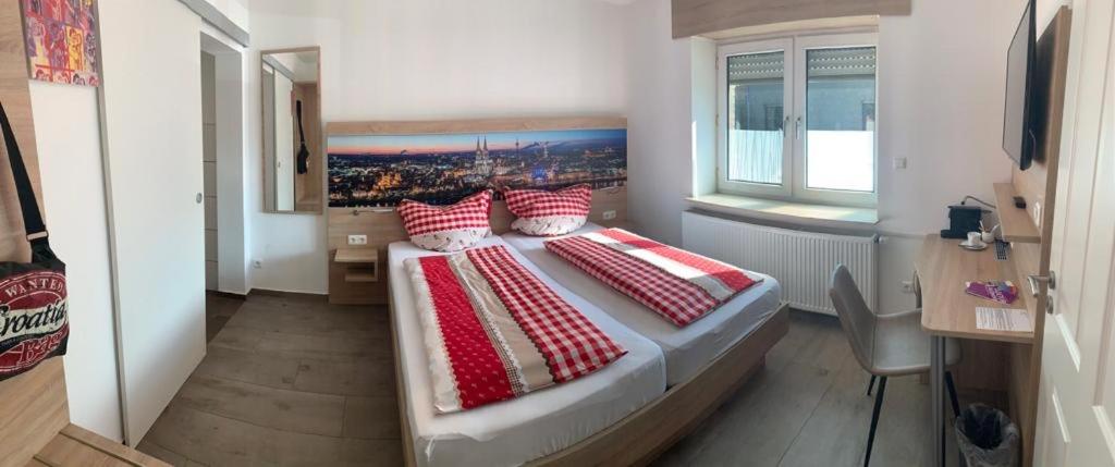 ein Schlafzimmer mit einem großen Bett mit roten und weißen Kissen in der Unterkunft Abtei Apartment Brauweiler in Pulheim