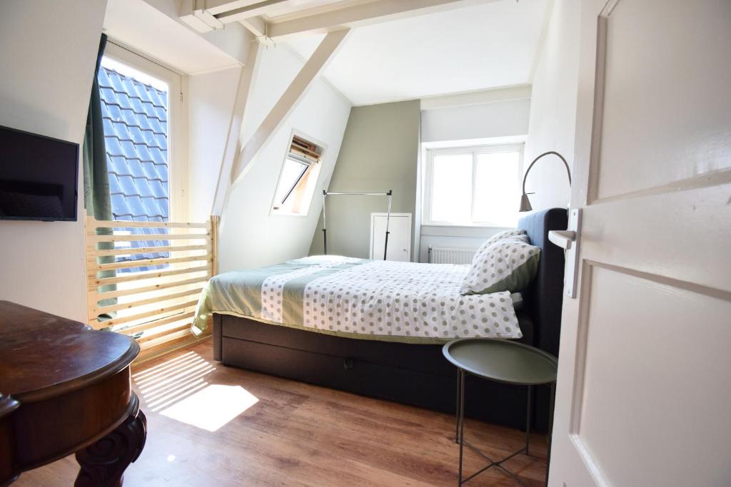 a bedroom with a bed and a desk and a window at Bed & Breakfast De Barrels in Groningen