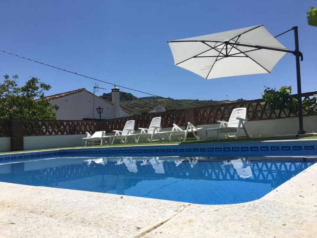 una piscina con sillas y sombrilla en CASA DE LOS ALAMOS, en Periana