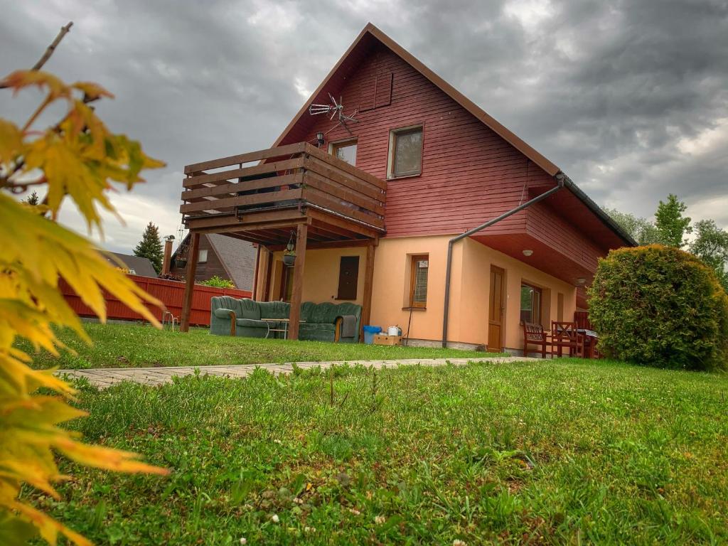 uma casa vermelha com um deque ao lado dela em Chaty Ivana 18 a 19 u Hustopecskych jezer em Hustopeče Nad Bečvou