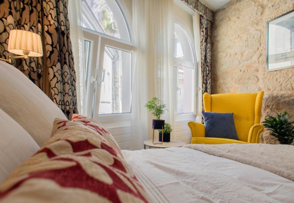 ムロスにあるCasa del anclaのベッドルーム1室(ベッド1台、黄色い椅子、窓付)