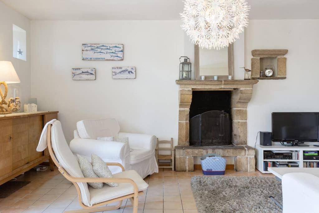 a living room with a fireplace and a chandelier at Maison de vacances en pierre entre terre et mer in Pluduno