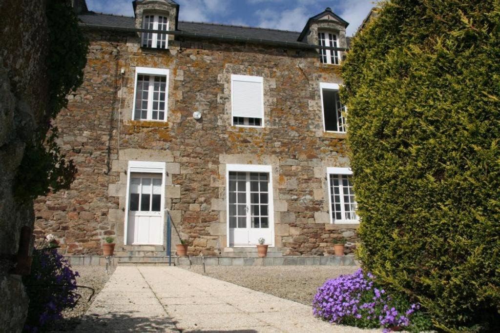 a brick building with white windows and a large bush at Maison de vacances en pierre entre terre et mer in Pluduno