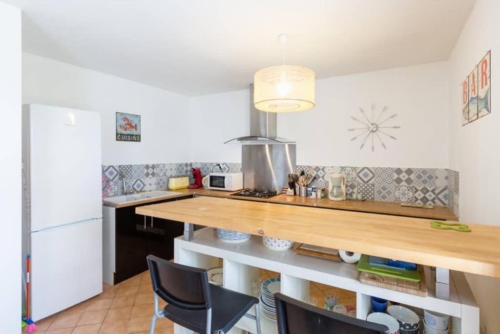 a kitchen with a counter with chairs and a refrigerator at Maison de vacances en pierre entre terre et mer in Pluduno