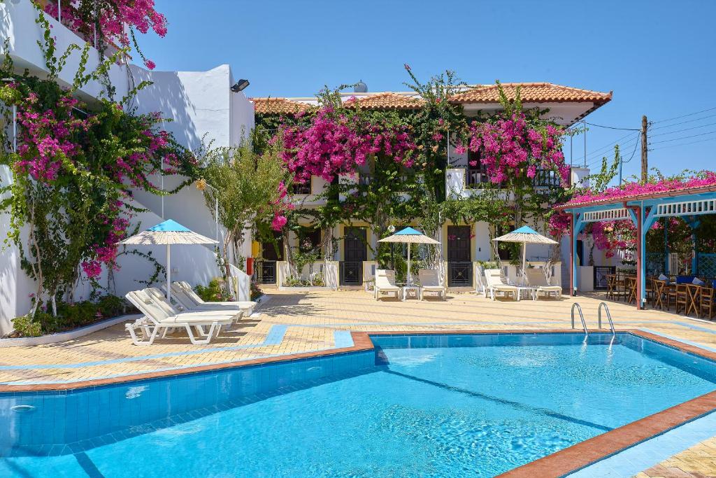 a pool in front of a building with pink flowers at Paul Marie in Hersonissos