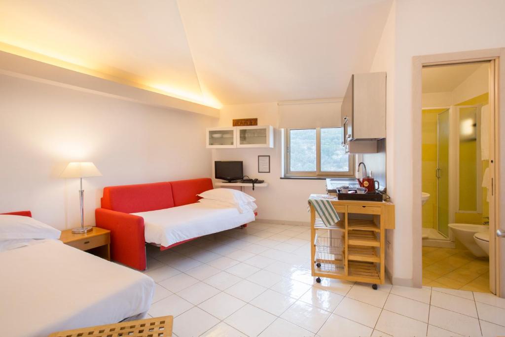 Cette chambre comprend deux lits et un canapé rouge. dans l'établissement Coltur Suites, à Sorrente