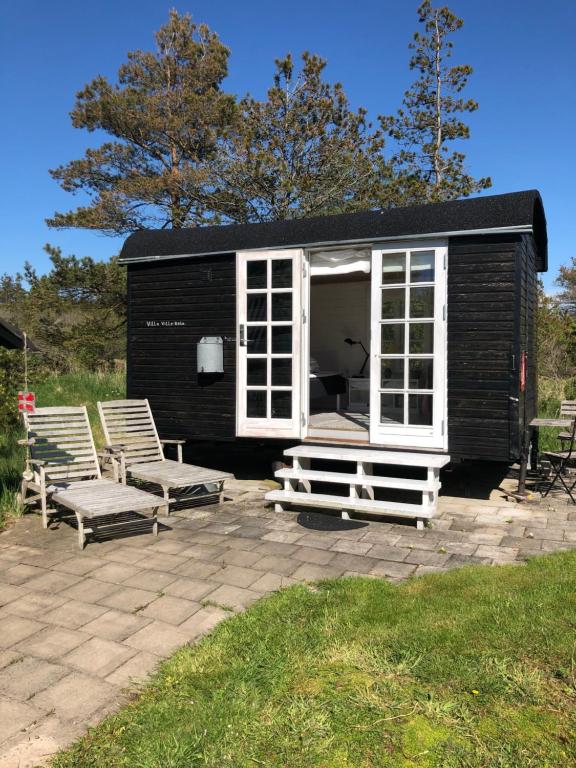 a small black shed with two chairs and a patio at Rødhus Gl. Skole B&B in Pandrup
