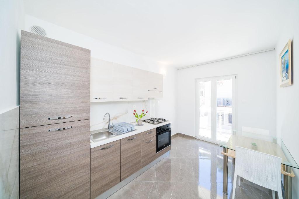 a kitchen with wooden cabinets and a sink and a table at Rooms &amp; Apartments Barišić in Mlini