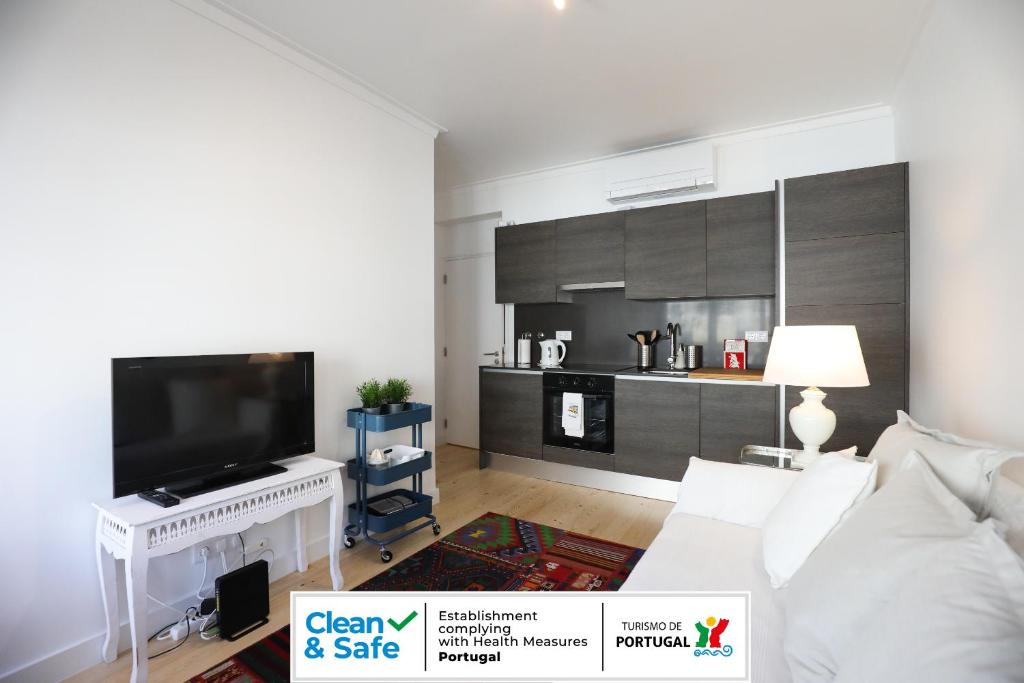 Central Lisbon Luxury Apartment في لشبونة: غرفة معيشة مع أريكة بيضاء وتلفزيون بشاشة مسطحة