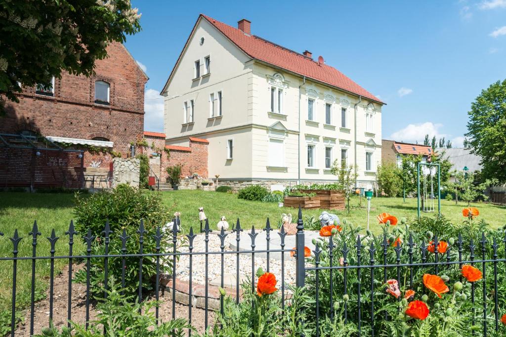 ein weißes Haus mit einem Zaun und Blumen in der Unterkunft Landpension-Kleeblatt in Würchwitz