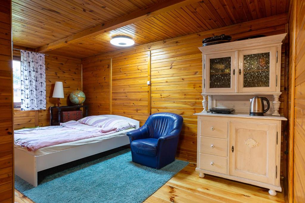 a bedroom with a bed and a blue chair at AB Domki całoroczne nad jeziorem in Stęszew