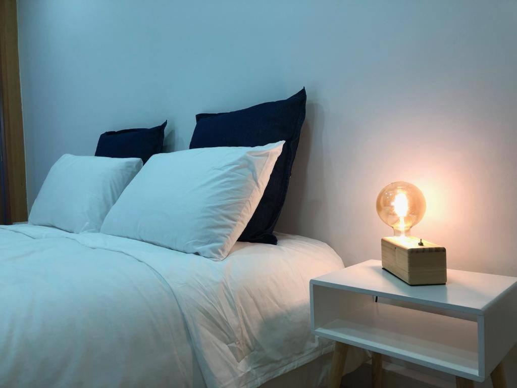 a white bed with a nightstand with a light on it at Casa do Rio - Riverside House in Seixal