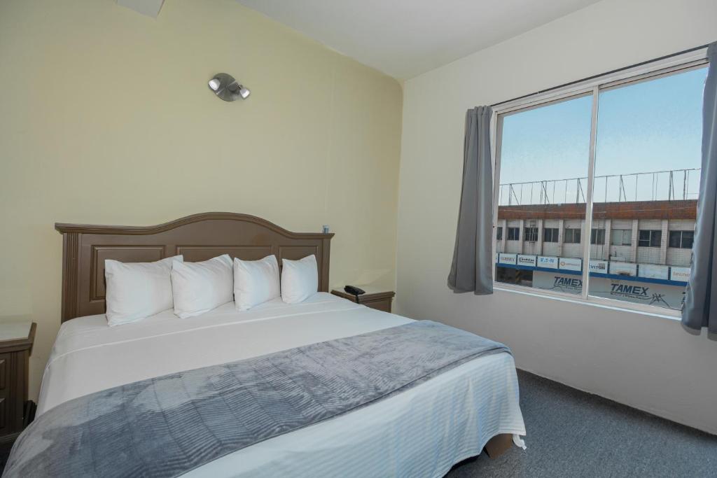 a bedroom with a bed and a large window at Hotel Plaza del Arco - Monterrey in Monterrey