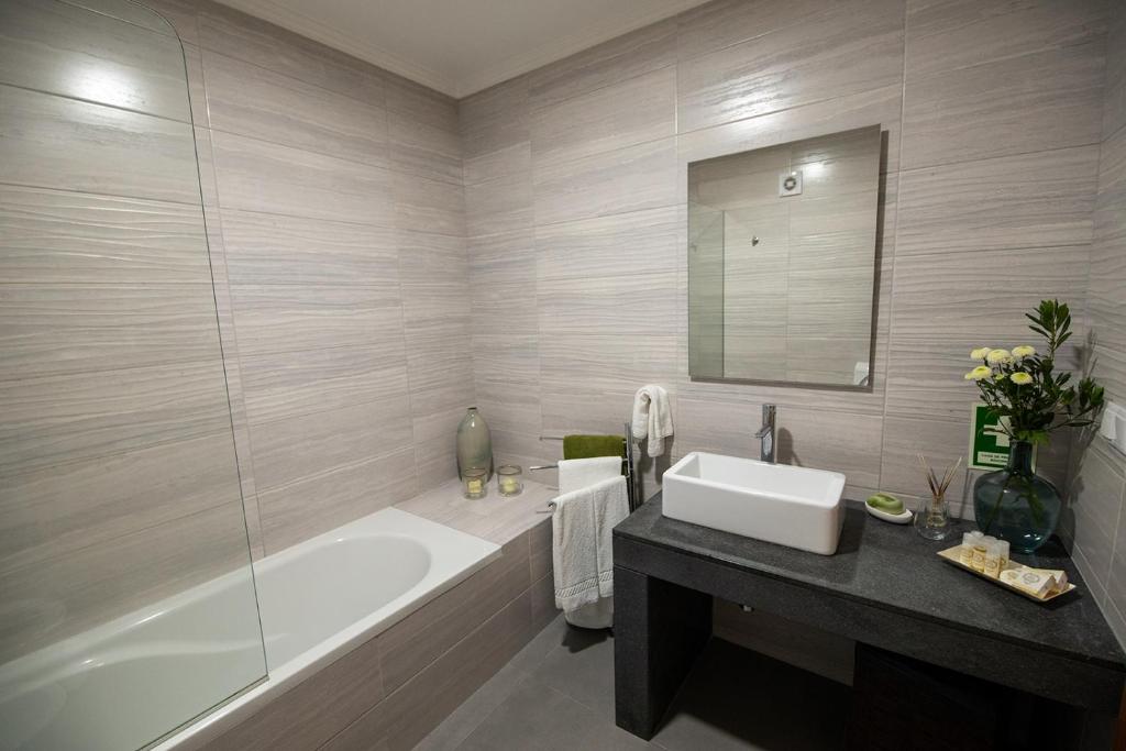 a bathroom with a tub and a sink and a mirror at Sete Cidades Quinta Da Queiró in Sete Cidades