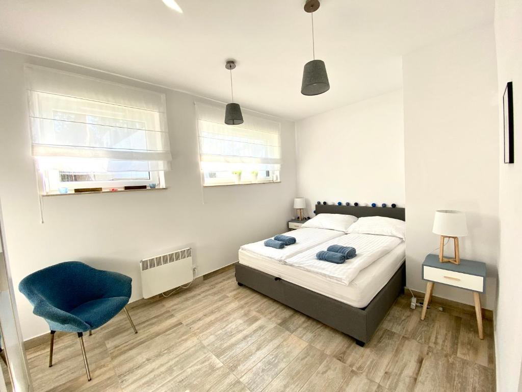 a bedroom with a bed and a blue chair at Sosnowe Zacisze Apartament in Łukęcin
