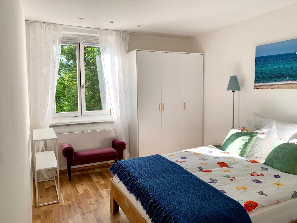 a bedroom with a bed and a chair and two windows at Sonnenhof - Ferienwohnung in Oberstaufen