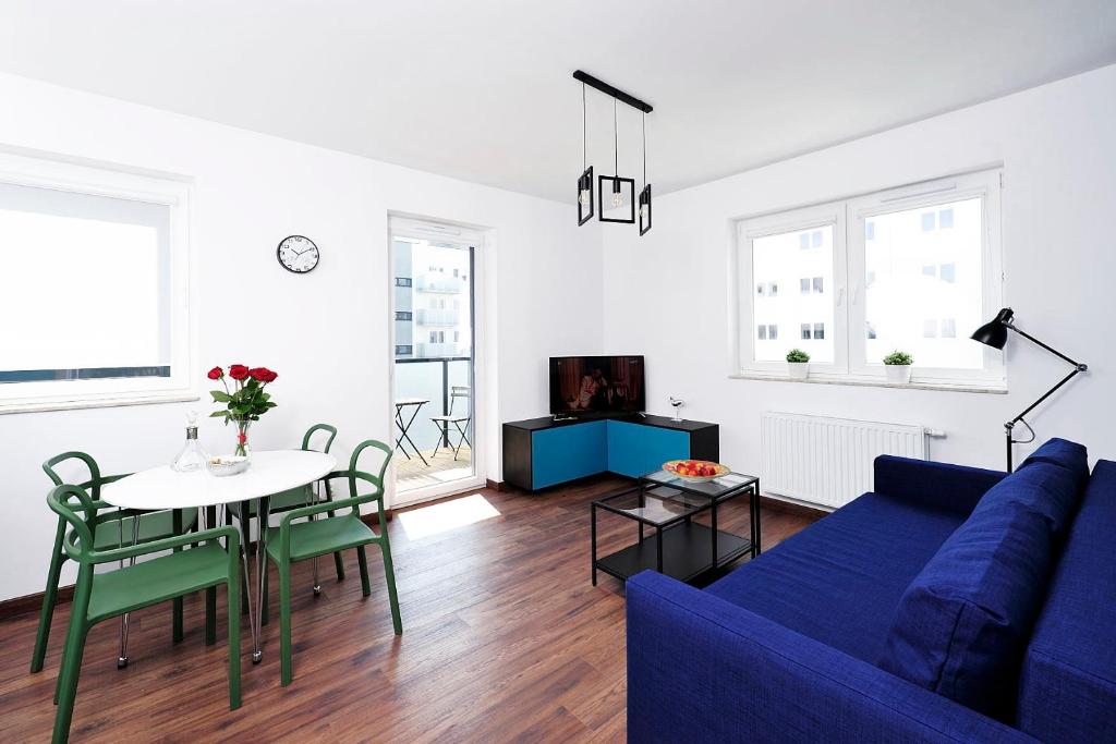 een woonkamer met een blauwe bank en een tafel bij Sleep Well Inżynierska in Wrocław