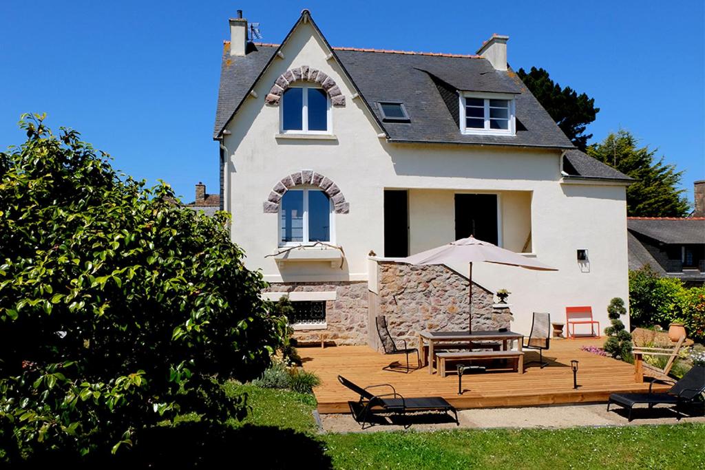 Cette maison dispose d'une terrasse avec une table et des chaises. dans l'établissement Kerpalud, maison néo-bretonne, près de Paimpol, à Ploubazlanec