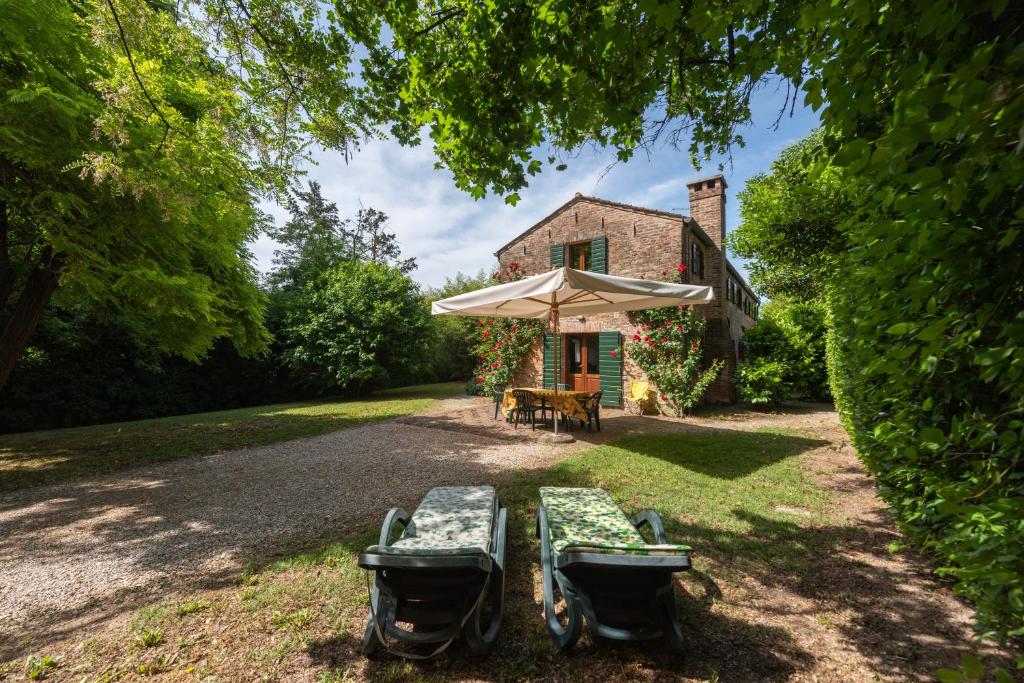 - une table de pique-nique et un parasol en face d'une maison dans l'établissement Country house pisani 120SQM, à Pernumia