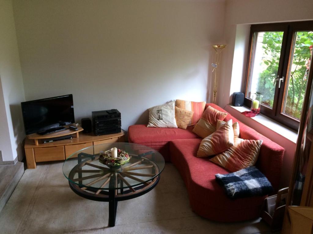 a living room with a red couch and a glass table at Ferienwohnung am Mozarthügel in Warstein