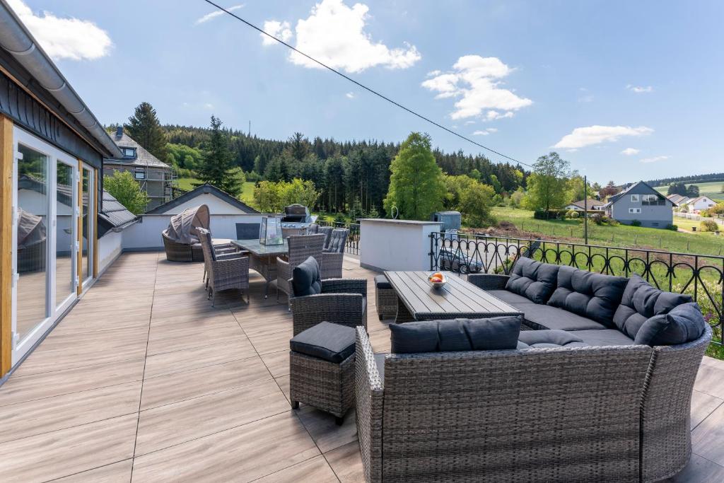 a patio with a couch and chairs on a deck at Altes Forsthaus - Ferienwohnung im Obergeschoss in Ormont