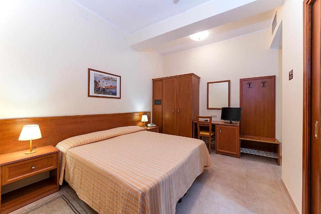 a hotel room with a bed and a desk at Il Nocchiero City Hotel in Soverato Marina