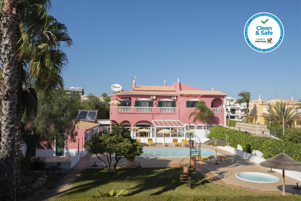 a pink house with a swimming pool in front of it at Solar de Mos in Lagos