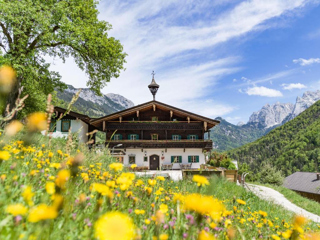 a house in the mountains with a field of flowers at Berg'k'hof Kaisertal - Alpine Hideaway in Ebbs