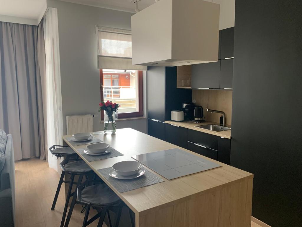 a kitchen with a table with plates and flowers on it at On THE MOON APARTAMENT in Gdańsk