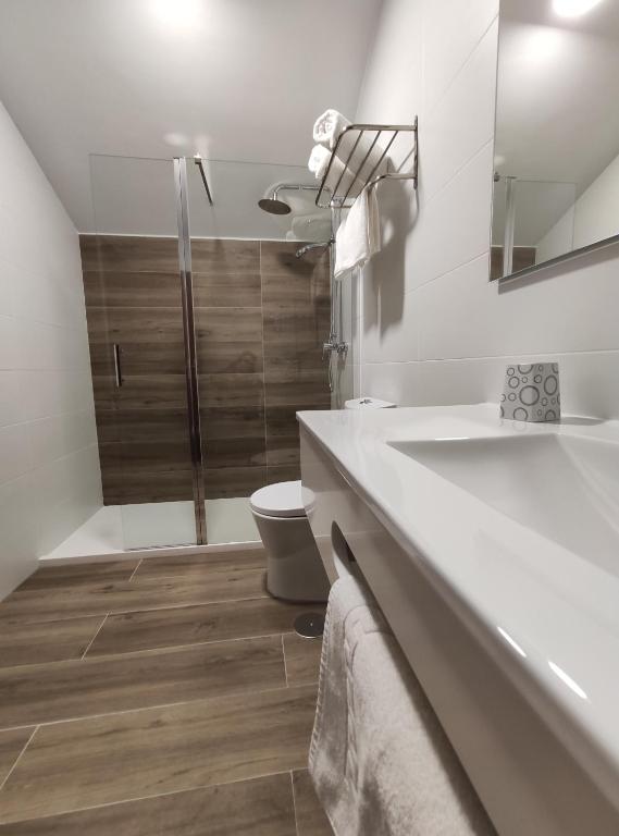 Un baño blanco con inodoro y lavabo. en Hostal-Restaurante Paris, en Forcarei