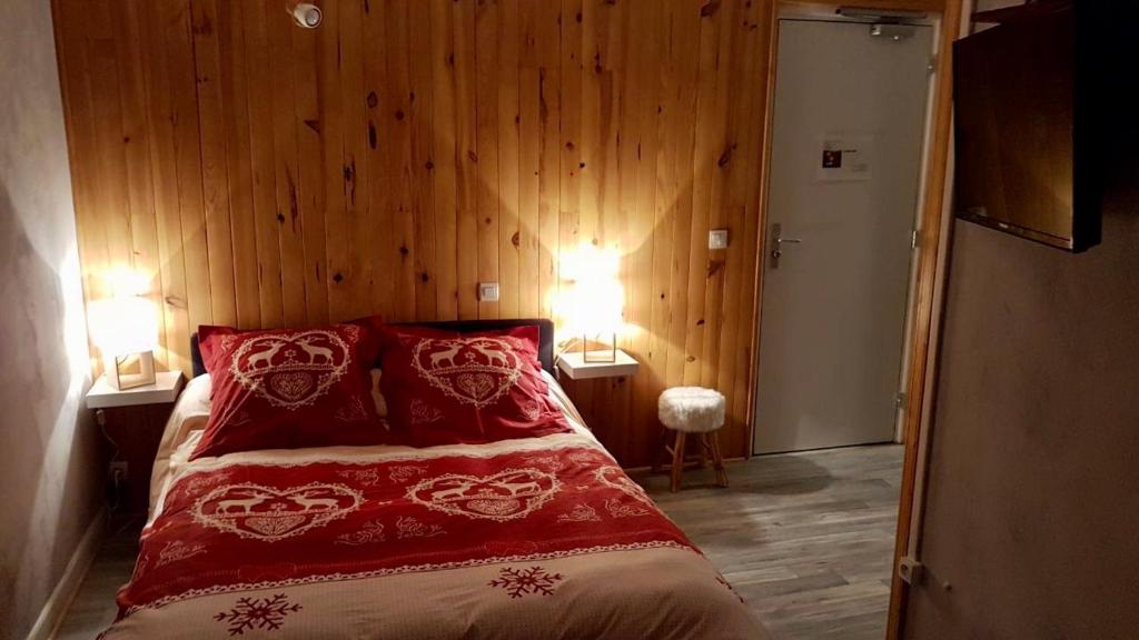 um quarto com uma cama com almofadas vermelhas e paredes de madeira em La Condaminoise em Condamine-Châtelard