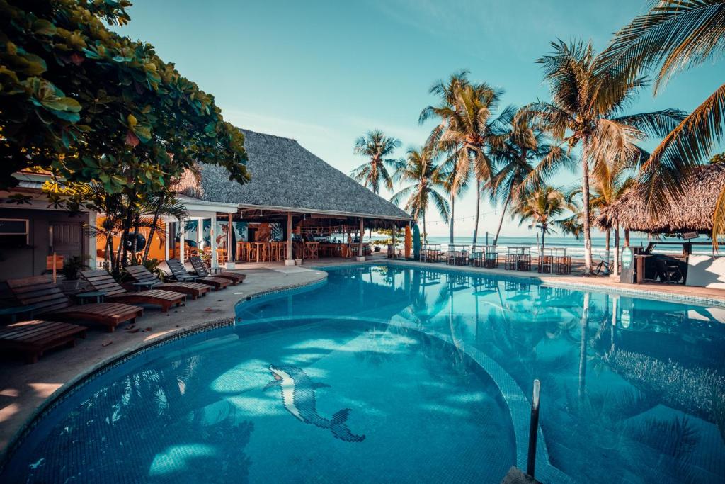 a swimming pool in front of a resort with palm trees at Selina Jaco in Jacó