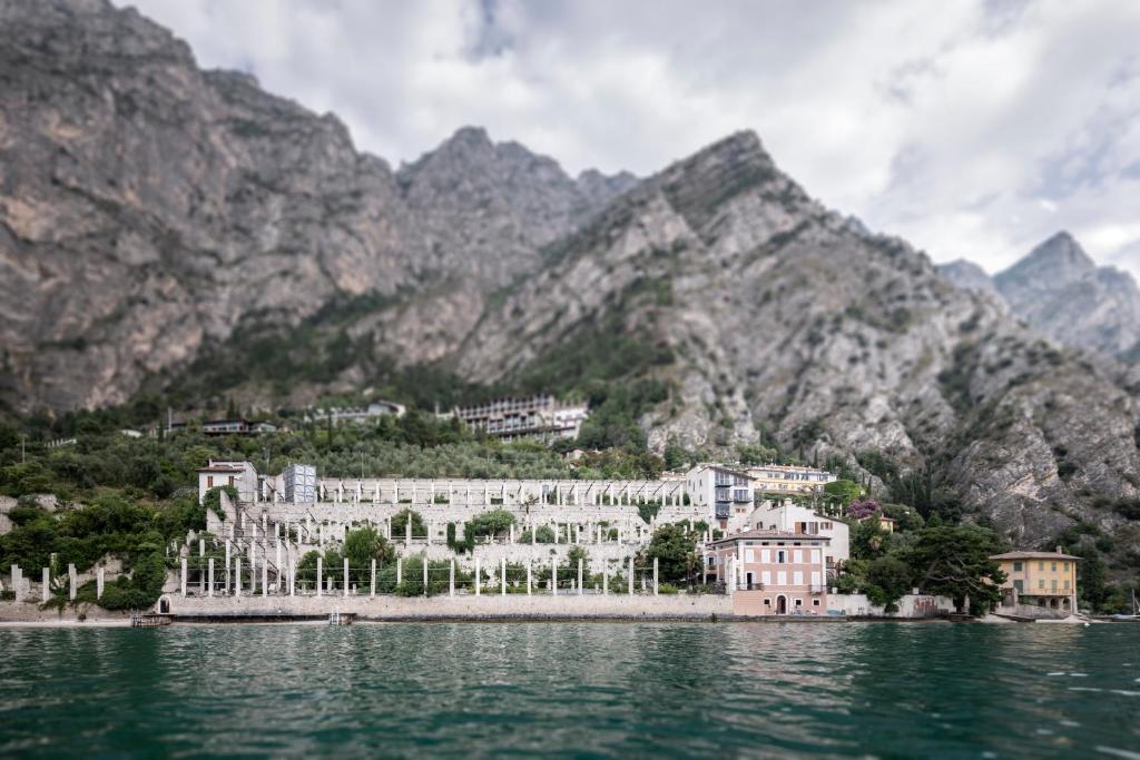 a building in the water with mountains in the background at Ca dela Nua in Limone sul Garda